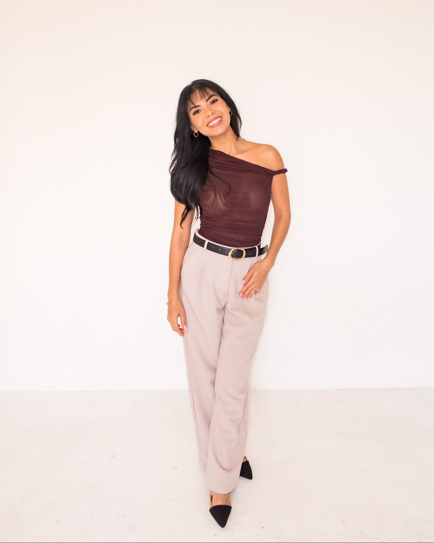 Woman wearing a brown off-shoulder top and beige pants on a white background